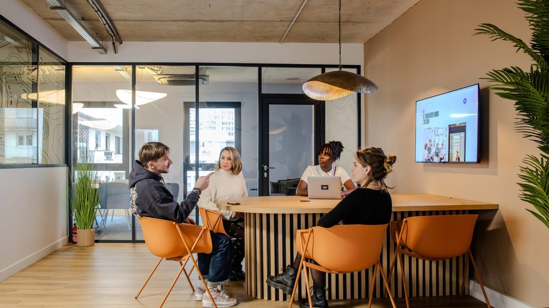 Équipe en réunion dans un bureau moderne aux chaises orangées