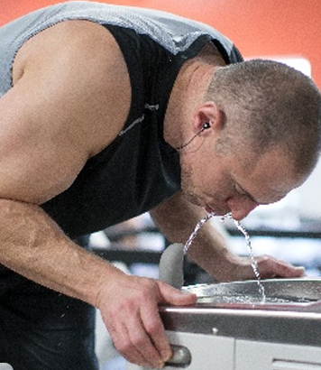 Athlète buvant à une fontaine à eau sans contact dans un gym